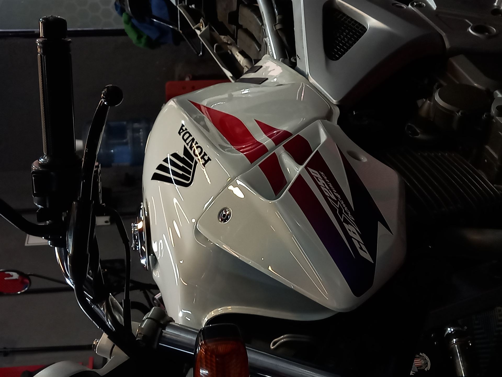 Carenado frontal de una moto Honda clásica blanca, roja y negra, con terminación de alto brillo tras el detailing.