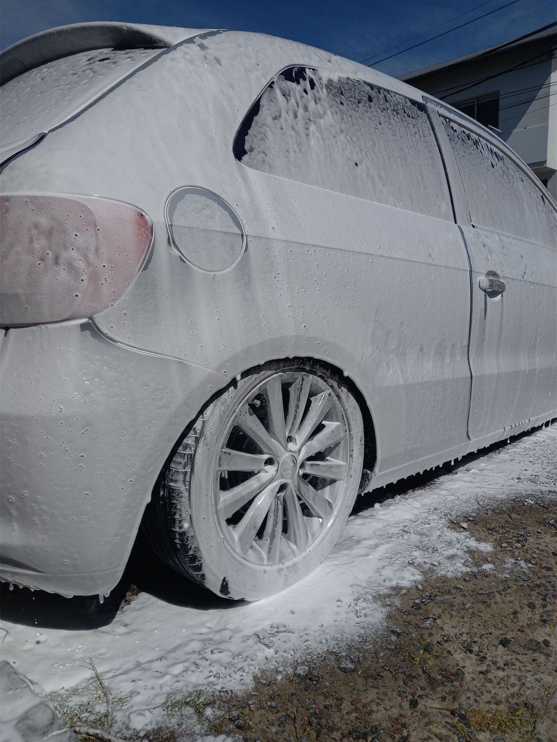 Auto cubierto con espuma blanca durante el prelavado, antes del proceso de detailing.