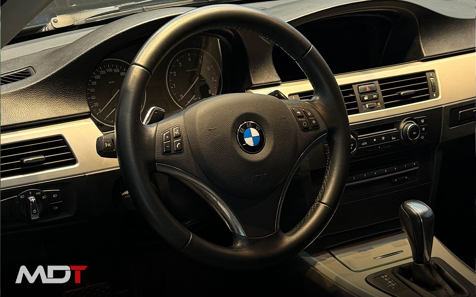 Volante y tablero de un interior premium recién detallado, con luz natural difusa.
