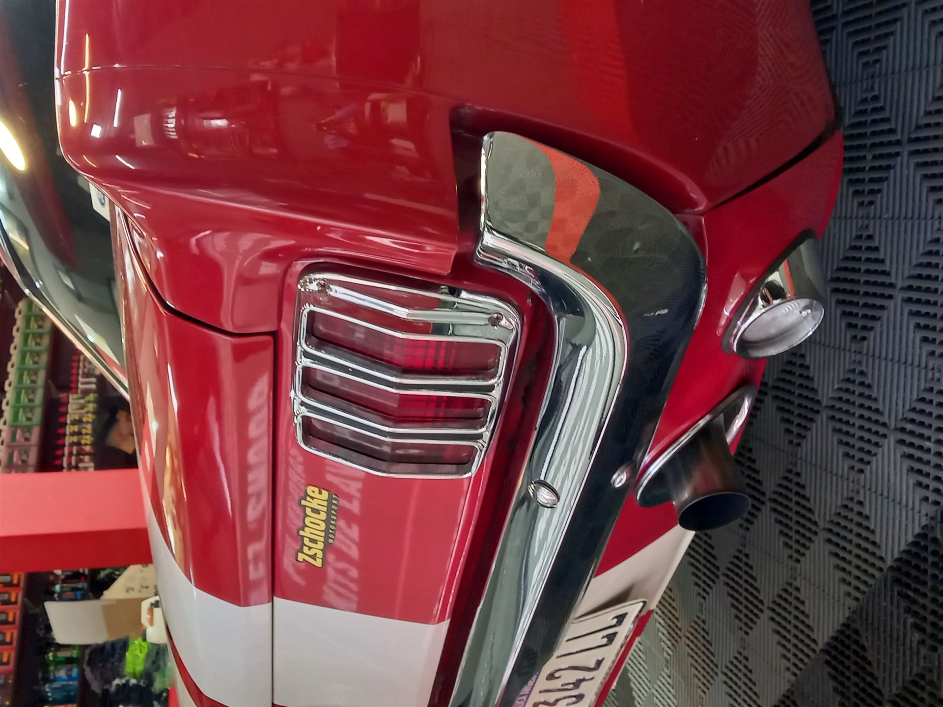 Detalle de la parte trasera de un auto clásico rojo con pintura de alto brillo, cromados y salida de escape, después del pulido.