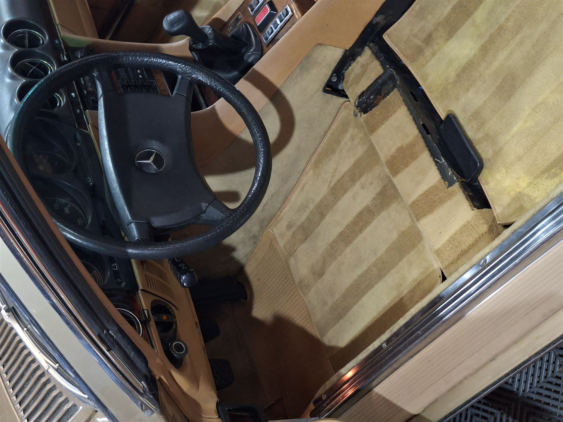 Interior clásico de un Mercedes-Benz con volante y tapizado en tonos beige, durante el proceso de detailing.