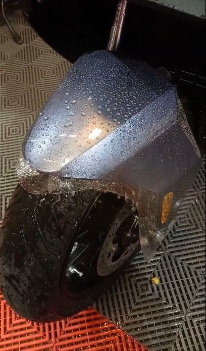 Guardabarros delantero de una moto con instalación de Paint Protection Film y gotas de agua perladas sobre la superficie.